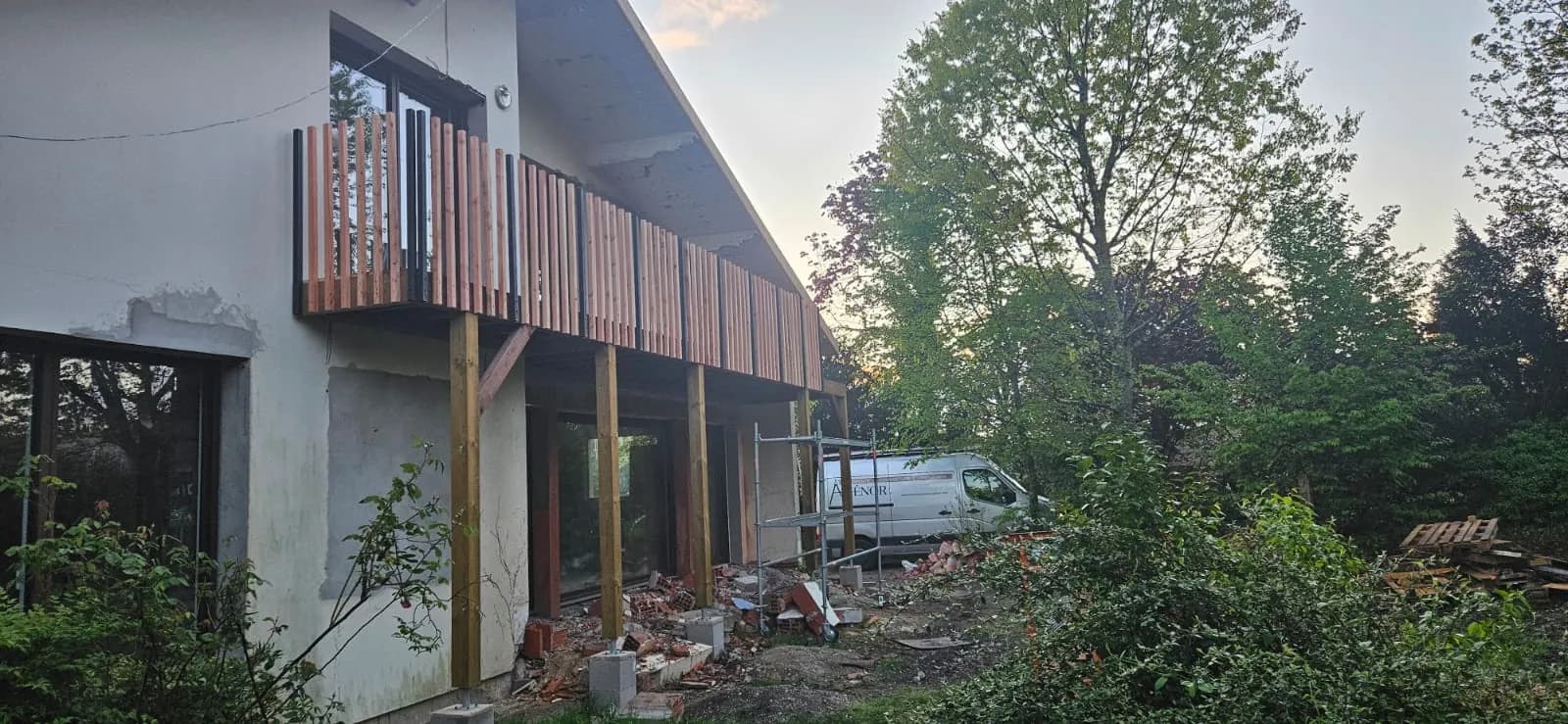 Balcon filant en bois sur pilotis le long d’une façade